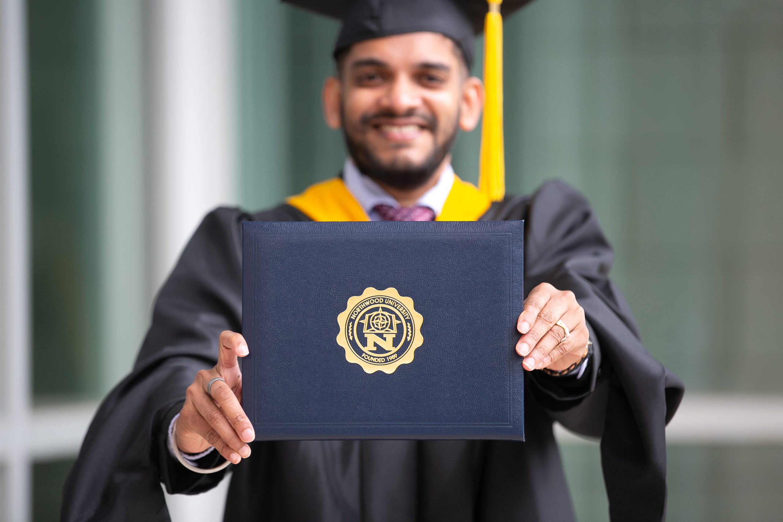International student smiling and holding his diploma