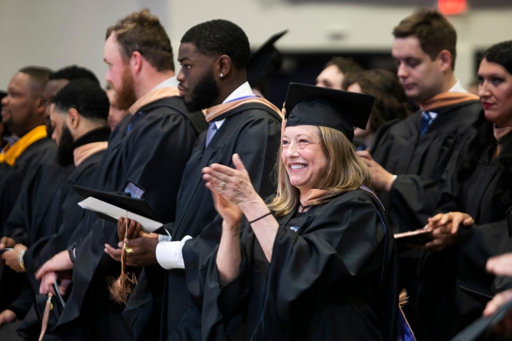 International faculty member clapping at graduation